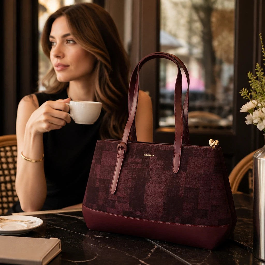 BRIKLYN CHRISBELLA burgundy structured tote handbag with textured geometric pattern on a cafe table